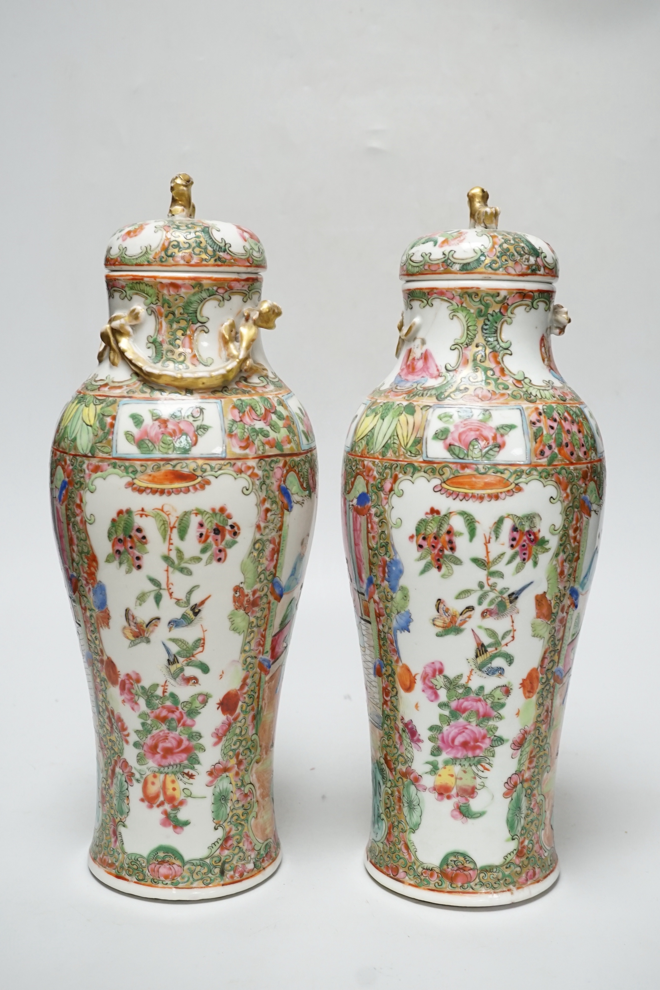 A pair of Chinese famille rose Canton baluster jars and covers with lion dog finials, 32cm high